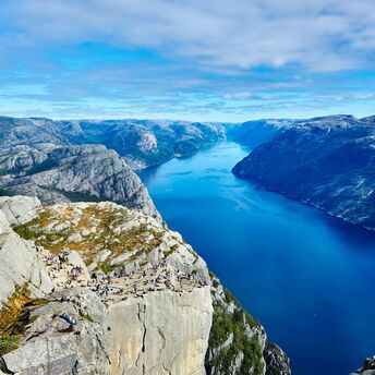 Tourists on a cliff overlooking a fjord in Norway
