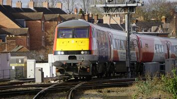 Transport for Wales train passing through a residential area with signal infrastructure