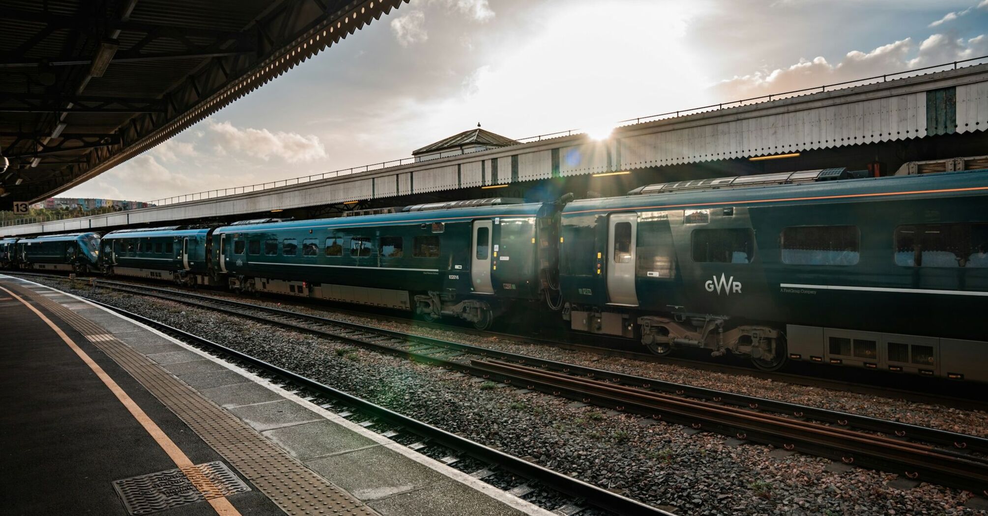 A Great Western Railway (GWR) train at a station platform during sunset in Bristol