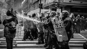 Police with shields spray water at a riot