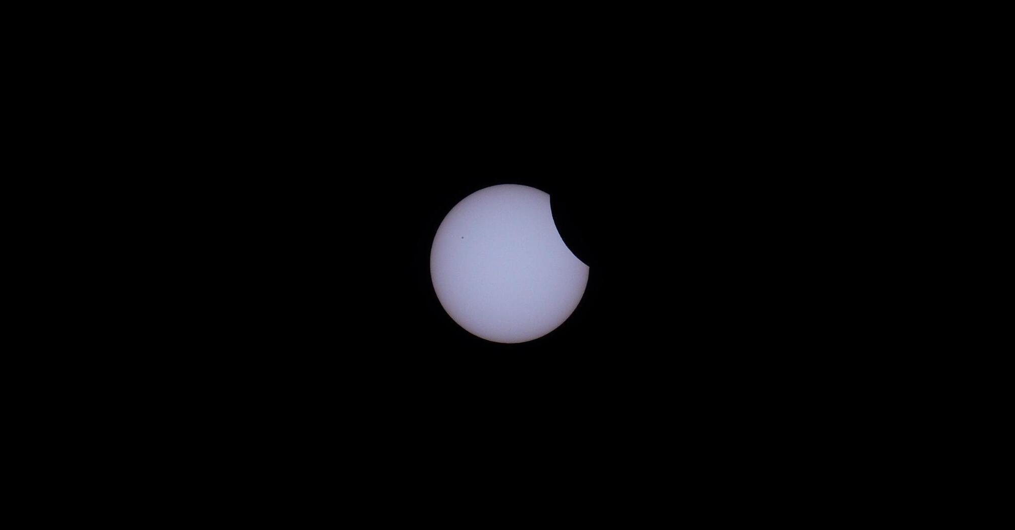 Partial solar eclipse with a portion of the Sun obscured by the Moon against a dark sky