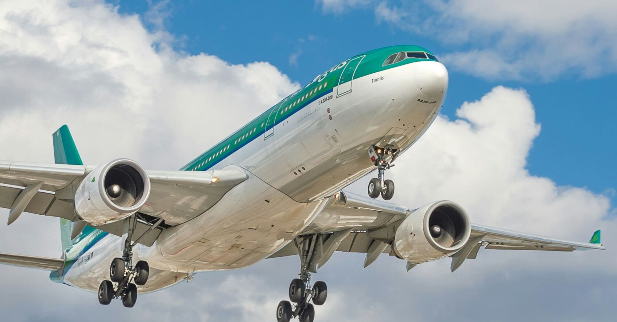 A large Aer Lingus airplane in flight against a backdrop of a partly cloudy sky