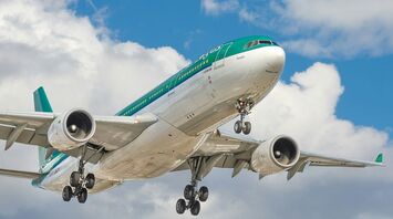 A large Aer Lingus airplane in flight against a backdrop of a partly cloudy sky