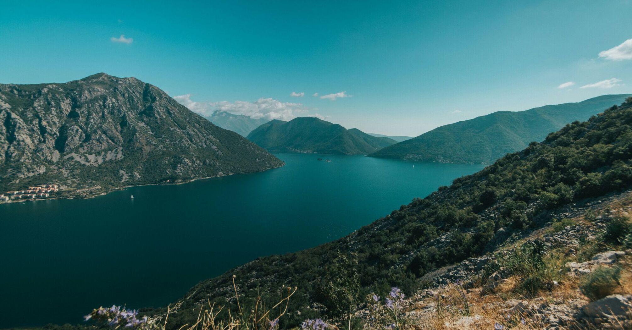 green mountains beside blue sea under blue sky during daytime