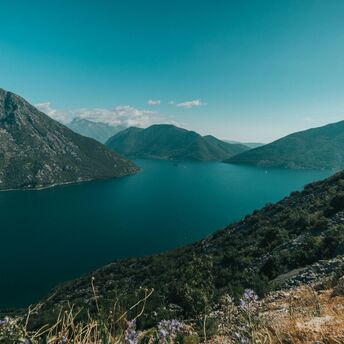 green mountains beside blue sea under blue sky during daytime