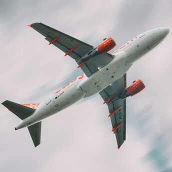 A low-angle shot of a easyJet airplane in flight with a cloudy sky background