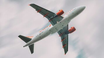 A low-angle shot of a easyJet airplane in flight with a cloudy sky background