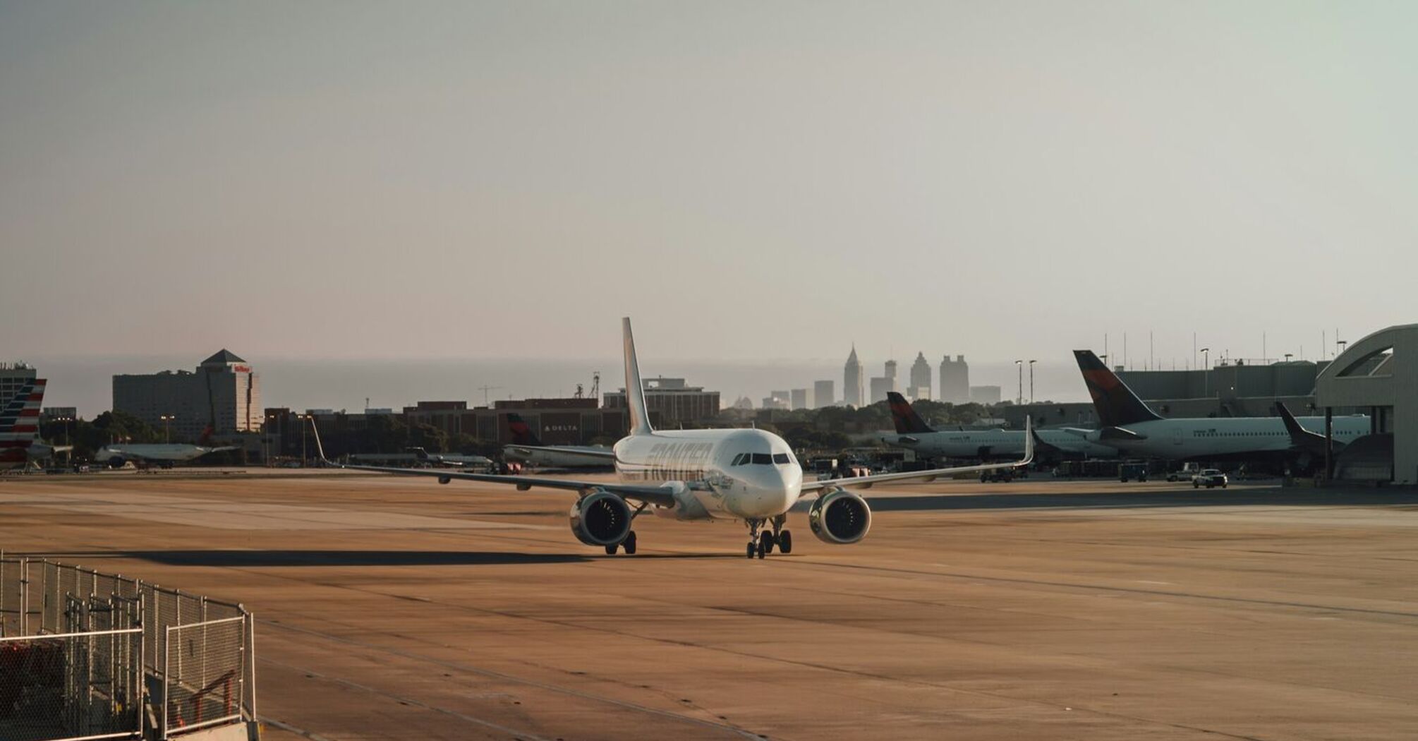 Airplane taxiing on a runway at an airport with city skyline in the background