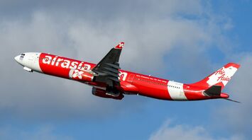 AirAsia airplane in flight against a blue sky with light clouds