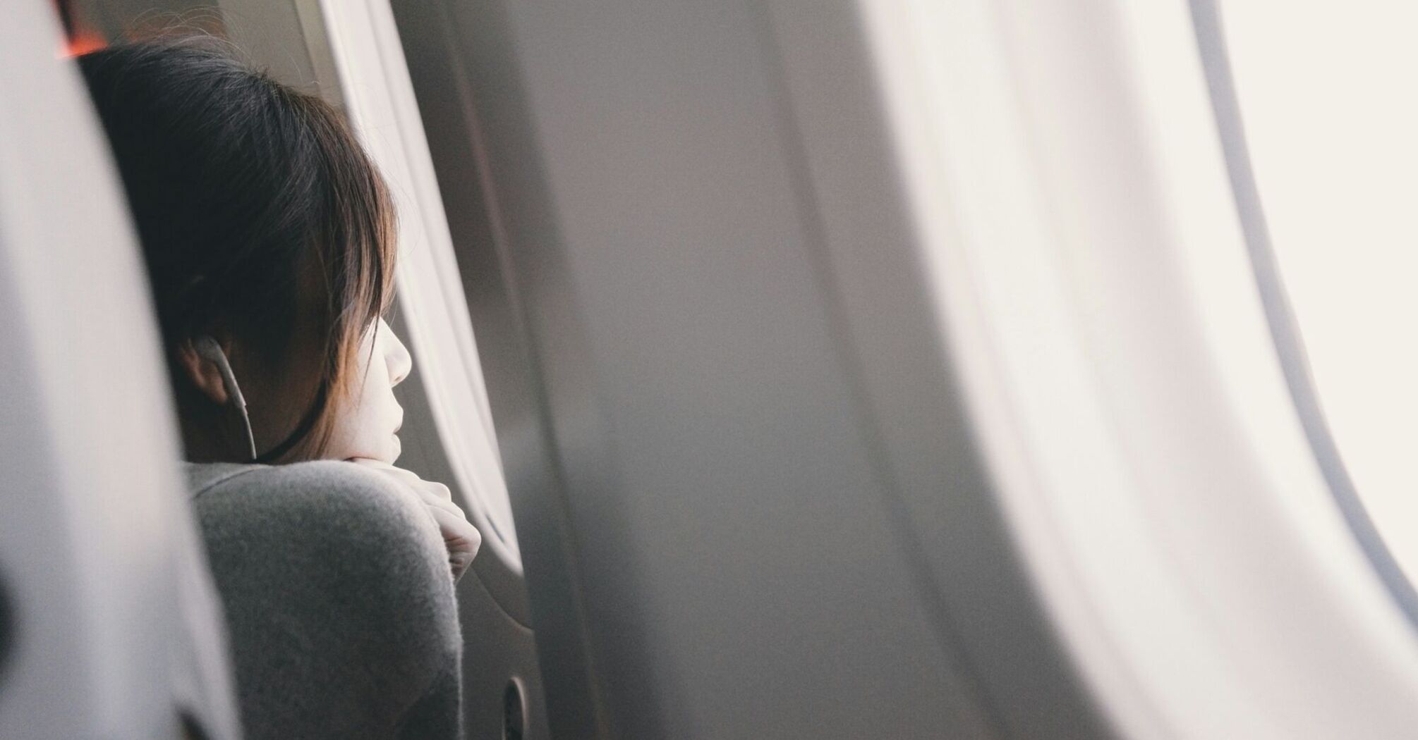 A person gazing out of an airplane window while listening to music