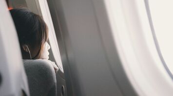 A person gazing out of an airplane window while listening to music