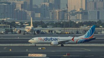 A Flydubai airplane on the runway at Dubai International Airport with a cityscape in the background