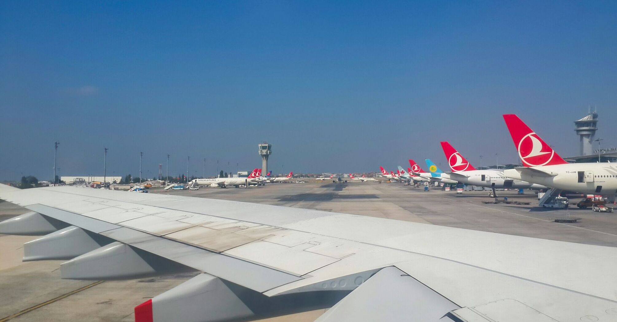 Turkish Airlines planes at an airport terminal with a control tower in the background