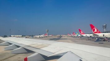 Turkish Airlines planes at an airport terminal with a control tower in the background