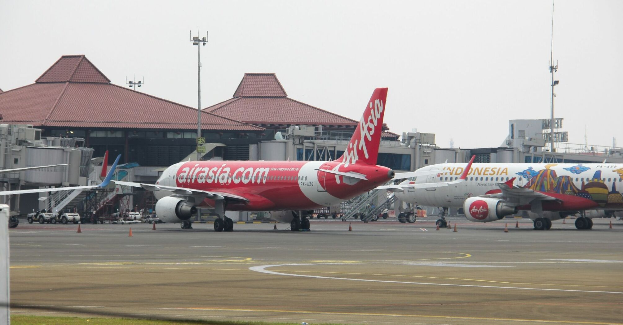 AirAsia airplane parked at an airport terminal with other planes in view