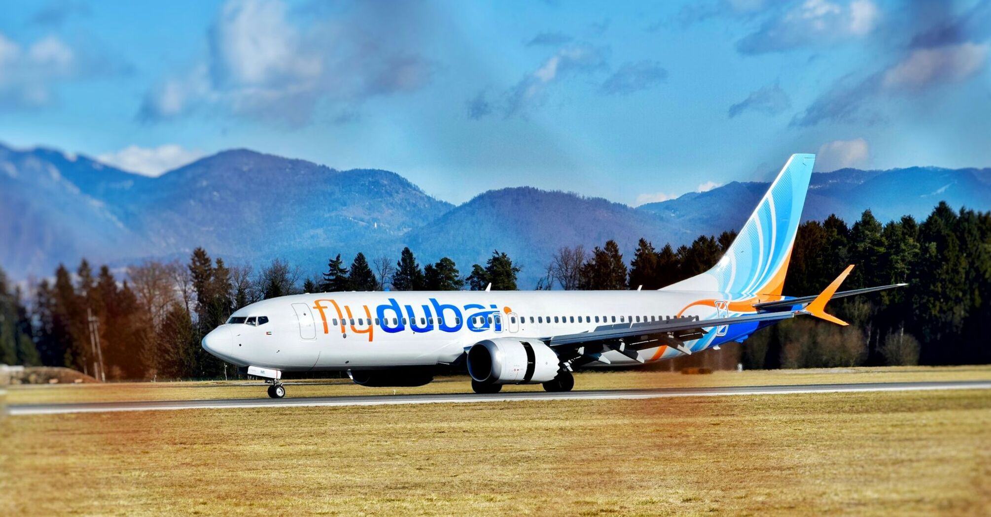 A flydubai airplane on a runway with mountains in the background