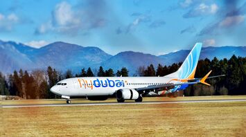 A flydubai airplane on a runway with mountains in the background