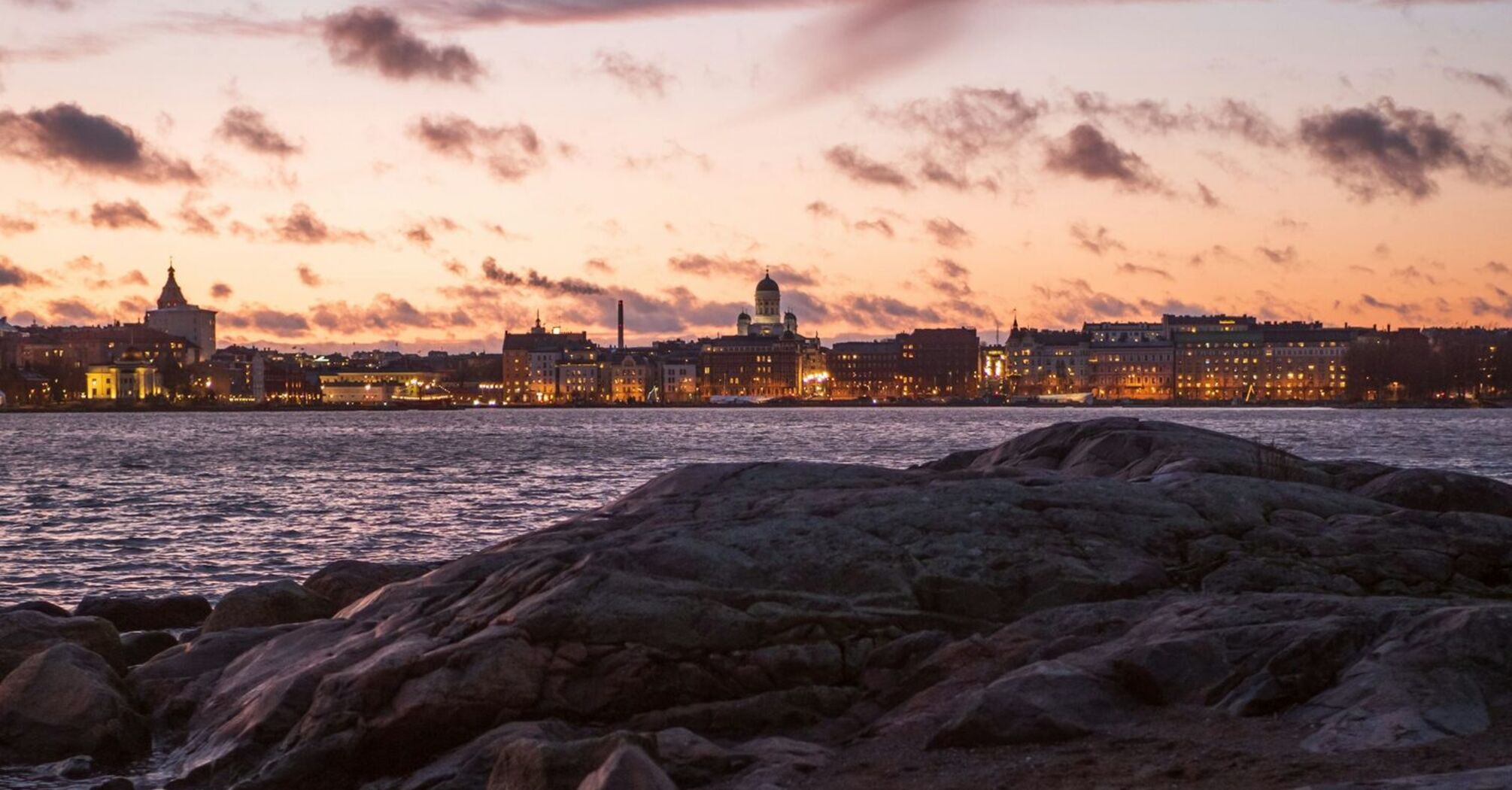 Rocky shoreline with the Helsinki skyline at sunset