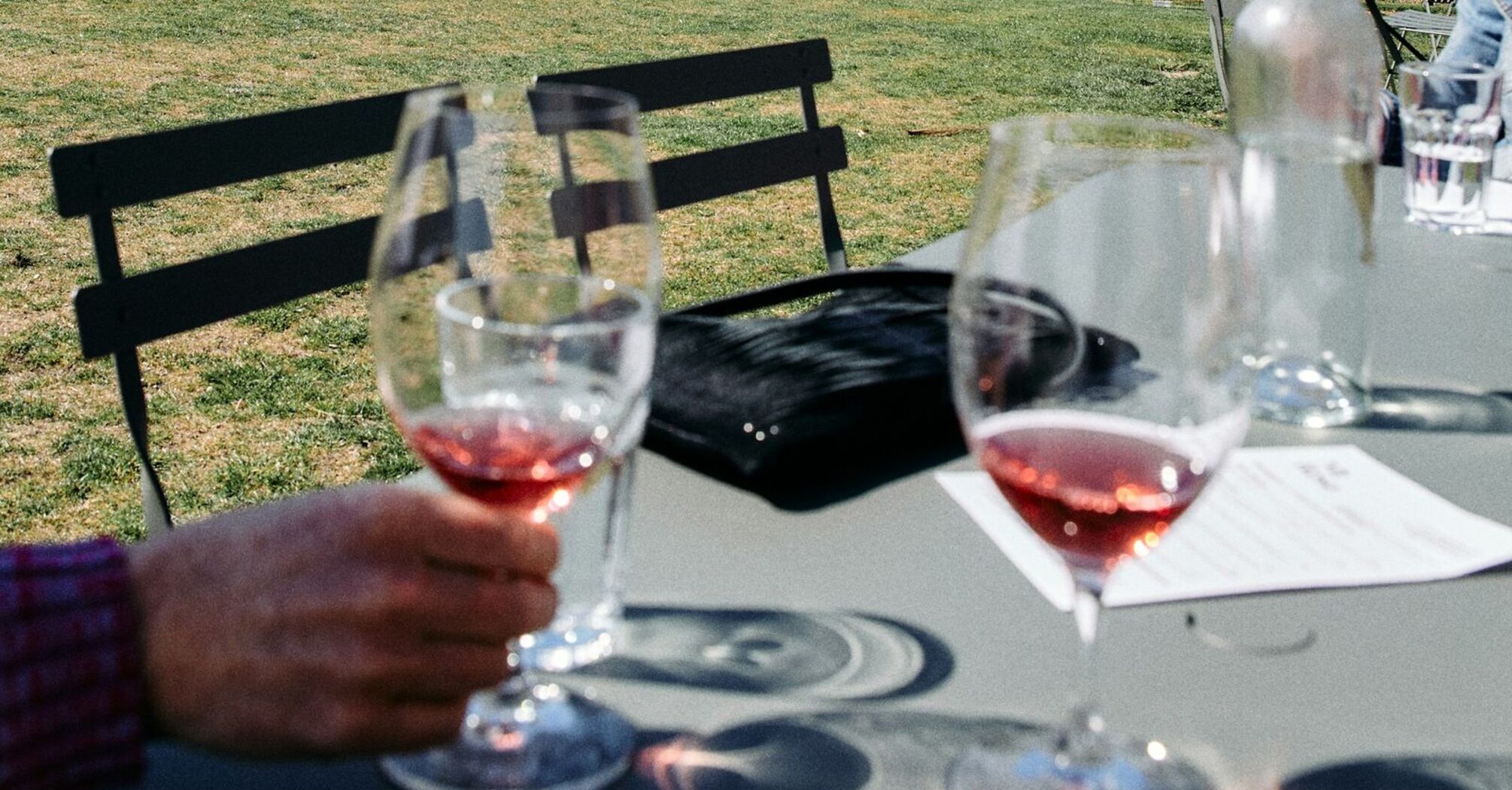 A picturesque vineyard nestled between mountain ranges, with wine glasses on a table in the foreground, hinting at a wine tasting experience