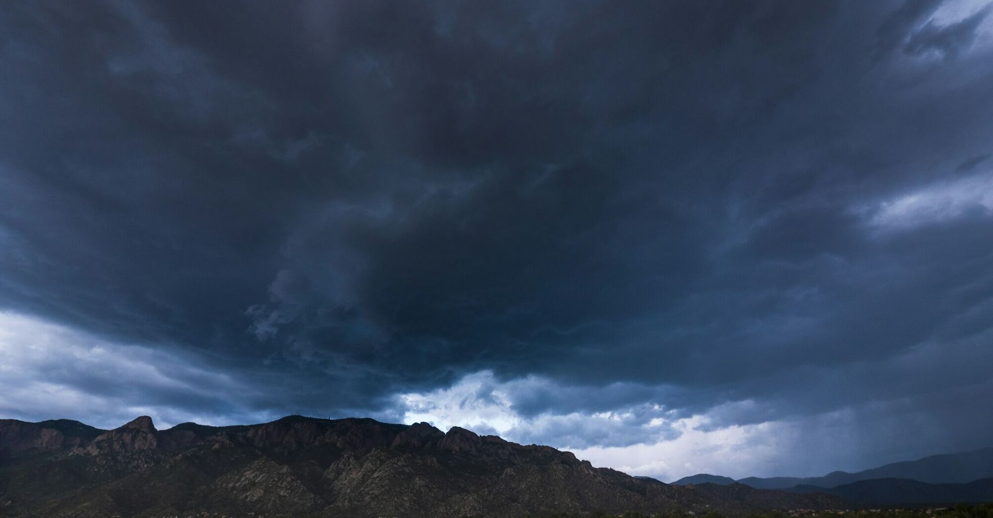 Dark storm clouds forming over a mountainous landscape