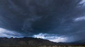 Dark storm clouds forming over a mountainous landscape