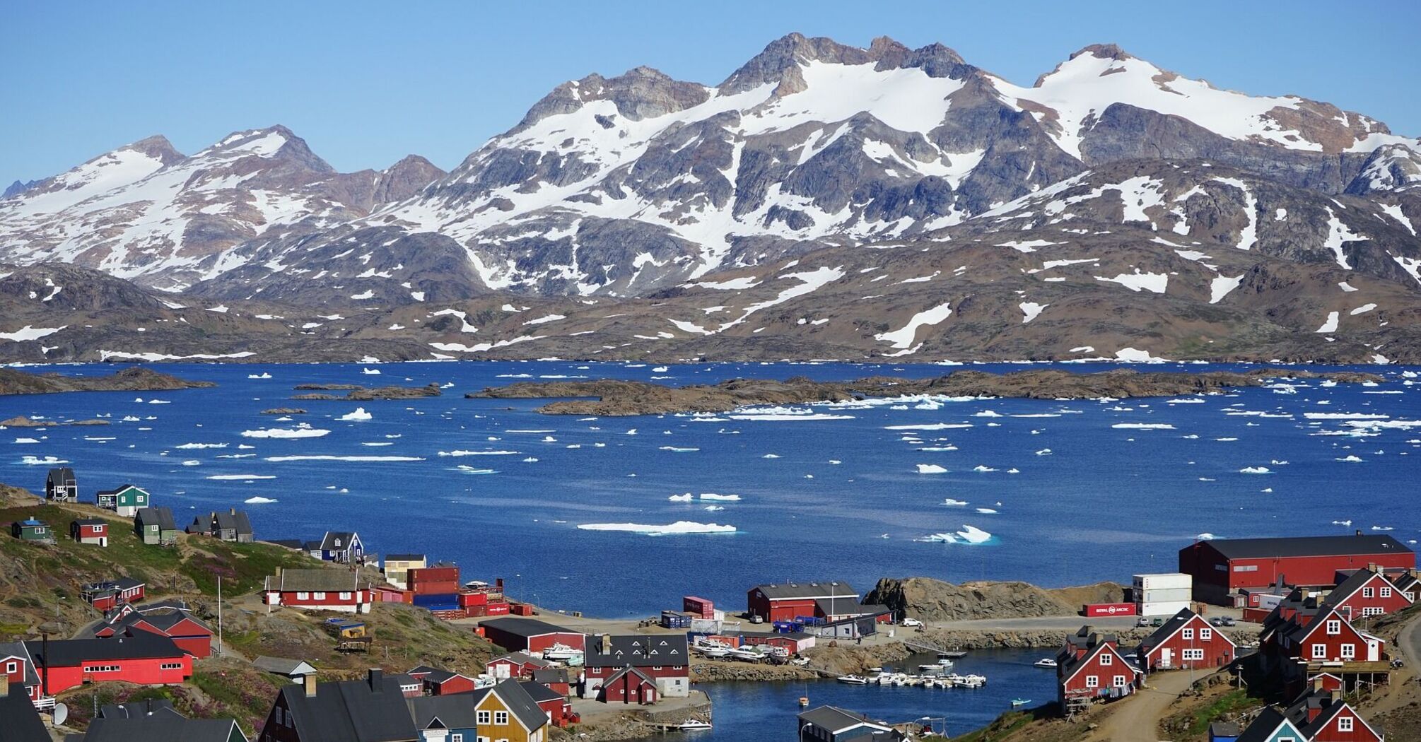 Colorful houses in a coastal Greenland town with snowy mountains in the background