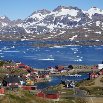 Colorful houses in a coastal Greenland town with snowy mountains in the background