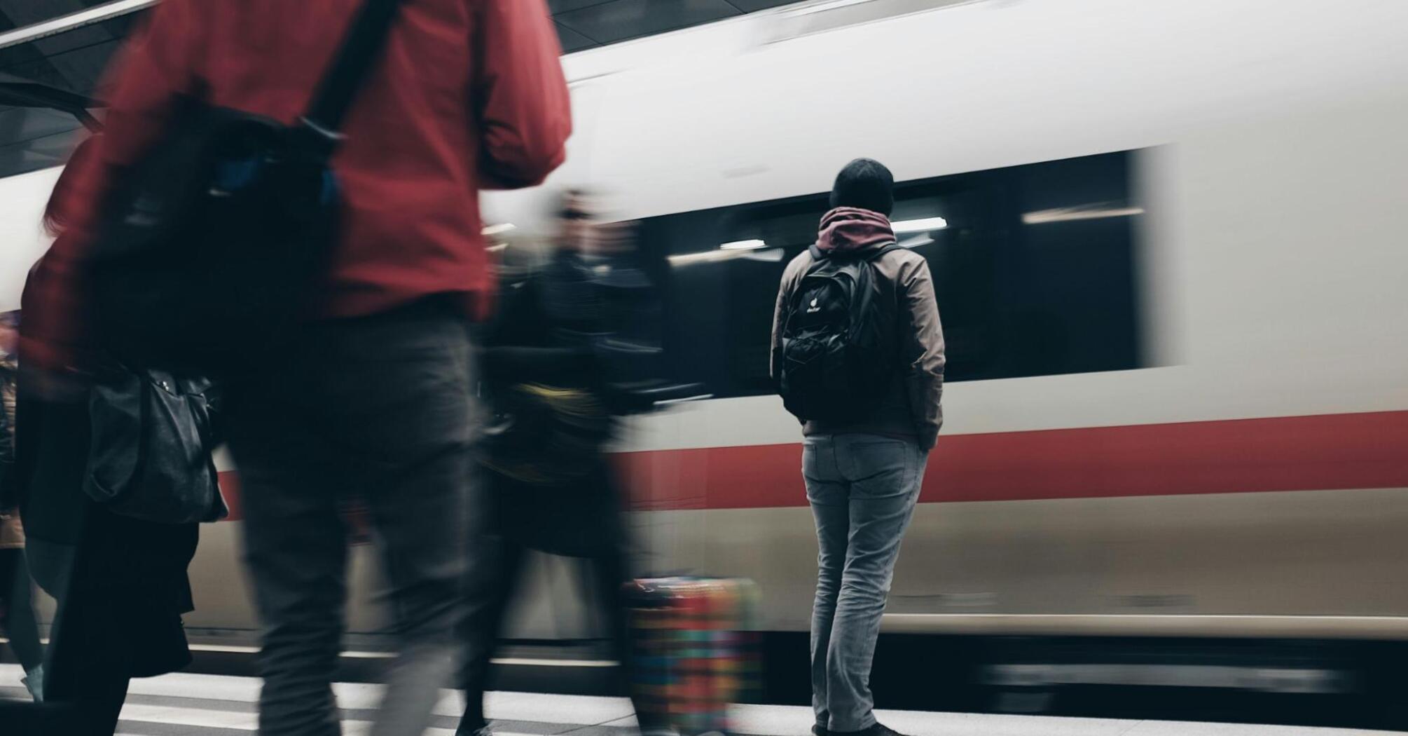 People waiting on a train platform as a train arrives