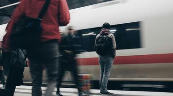 People waiting on a train platform as a train arrives