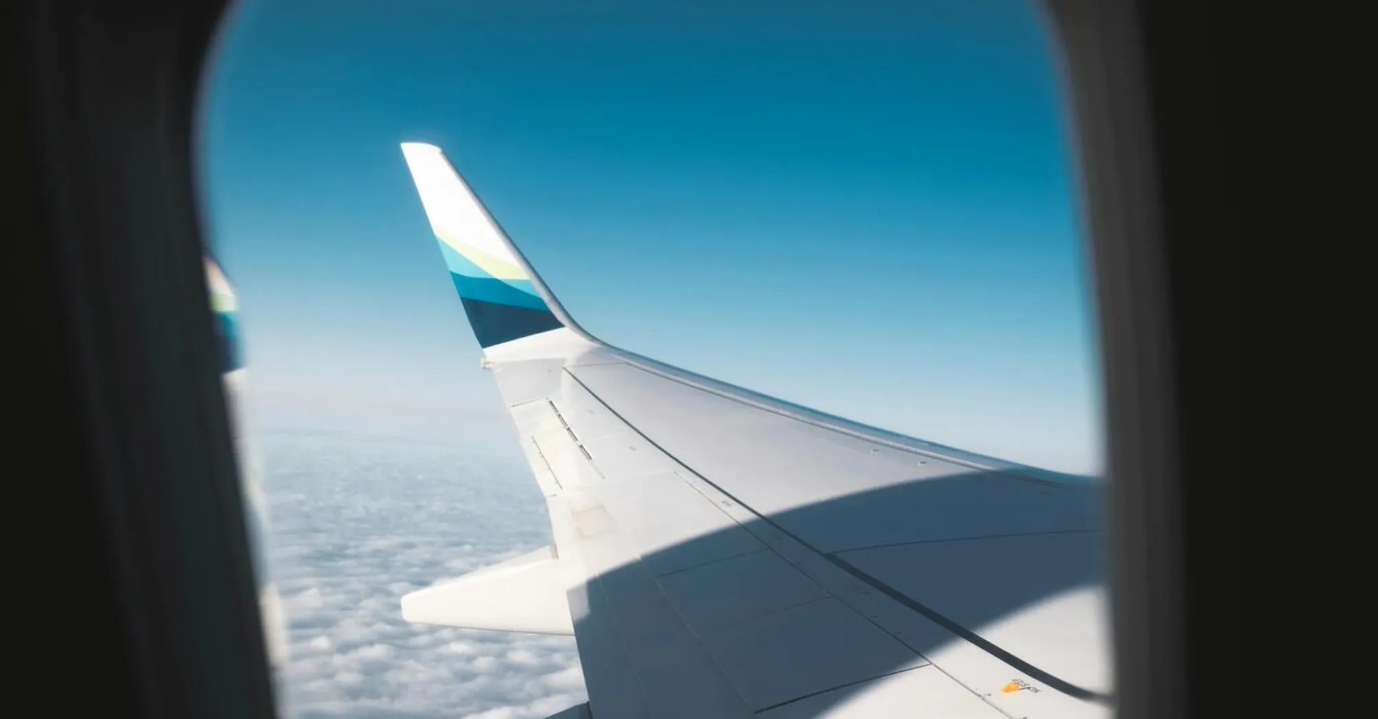 View of an airplane wing from the window in flight above the clouds