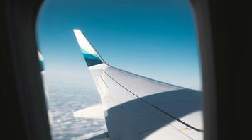 View of an airplane wing from the window in flight above the clouds