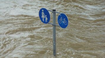 Flood waters submerge a pedestrian and bicycle sign