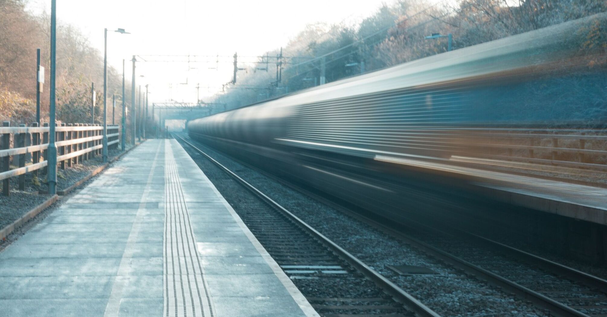 A fast-moving train passing through a quiet, empty station platform