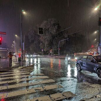 Rainy night at a city intersection with cars on wet streets