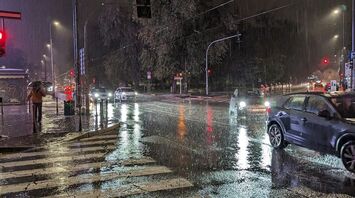 Rainy night at a city intersection with cars on wet streets