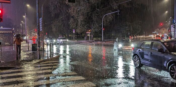 Rainy night at a city intersection with cars on wet streets