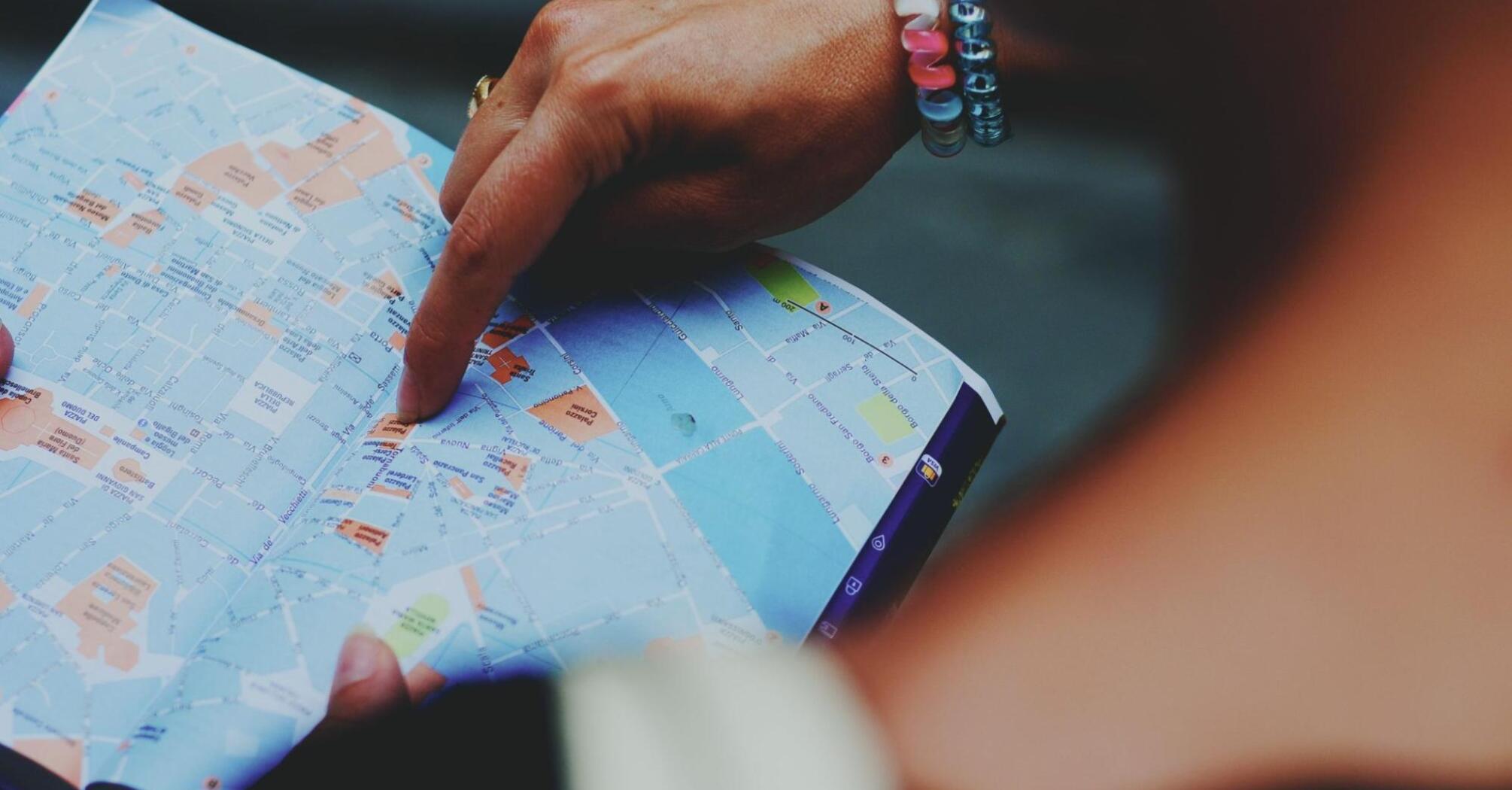 A person pointing to a map with their finger, highlighting travel routes