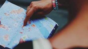 A person pointing to a map with their finger, highlighting travel routes