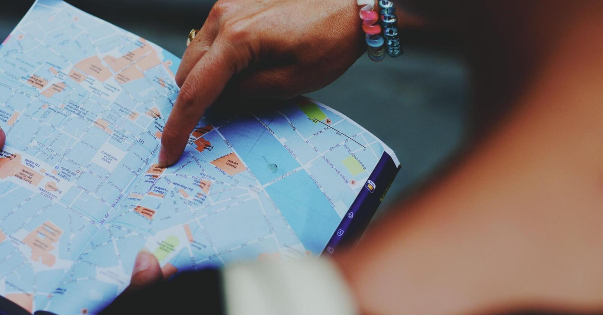 A person pointing to a map with their finger, highlighting travel routes