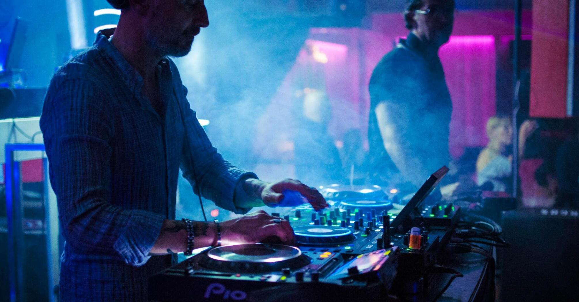 DJ mixing tracks at a club party with colorful lights