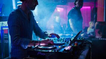 DJ mixing tracks at a club party with colorful lights
