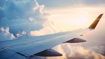 Airplane wing against a backdrop of clouds during sunset