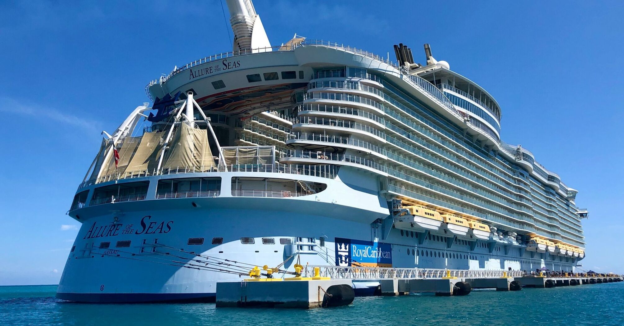 Royal Caribbean's Allure of the Seas docked in port under clear blue skies