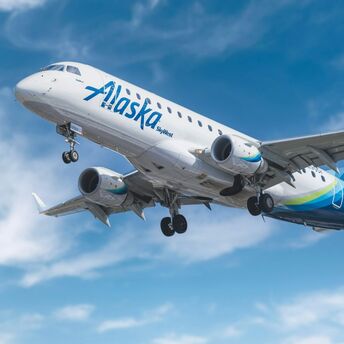 Alaska Airlines plane in flight under clear blue skies