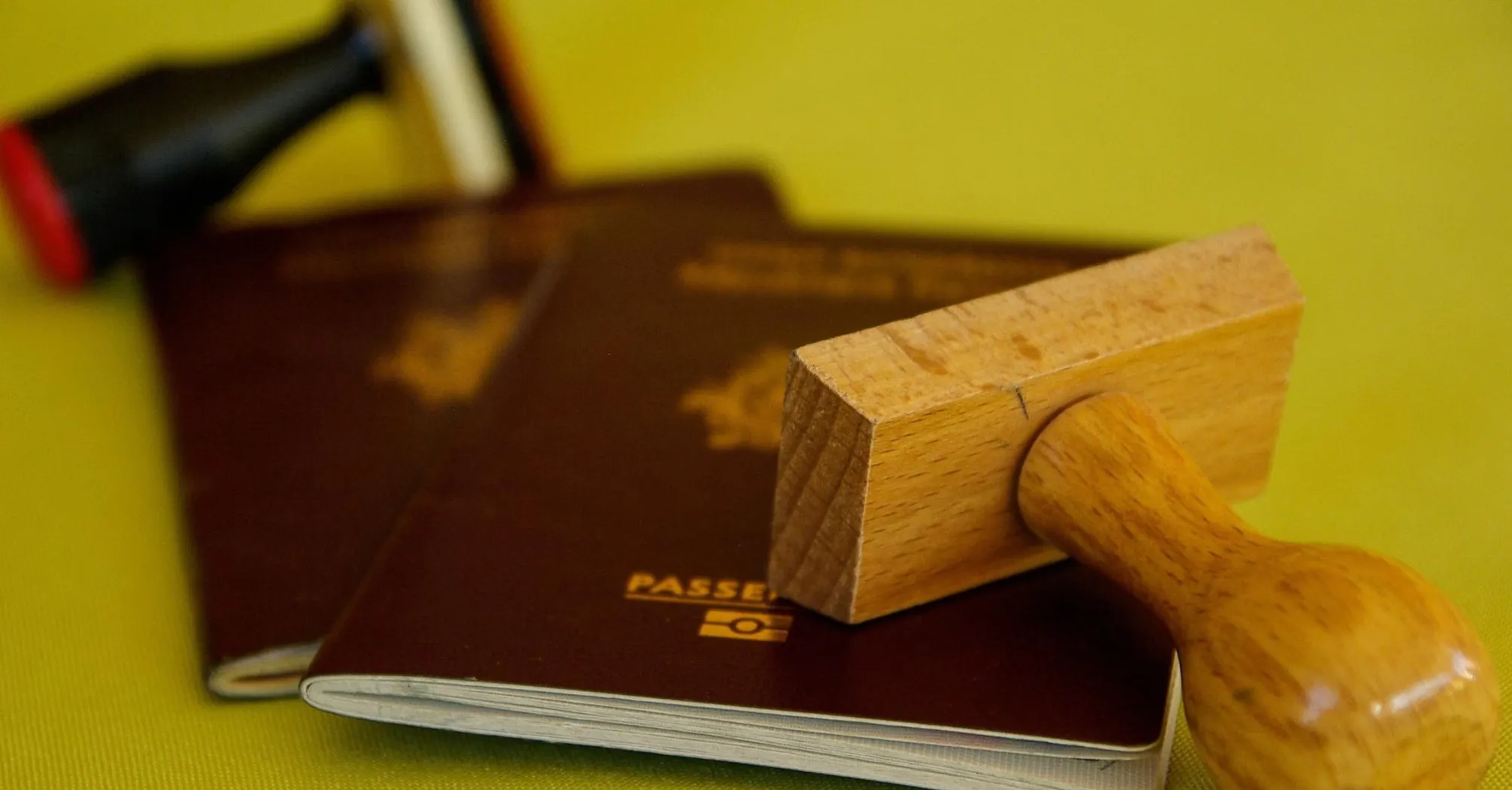 Two passports with a wooden stamp on top, representing traditional passport stamping