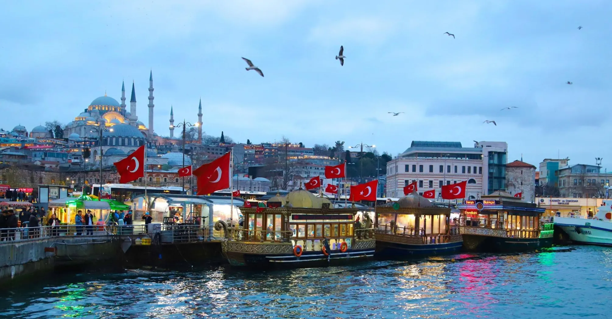 Traditional Turkish boats with flags docked at a busy waterfront in Istanbul