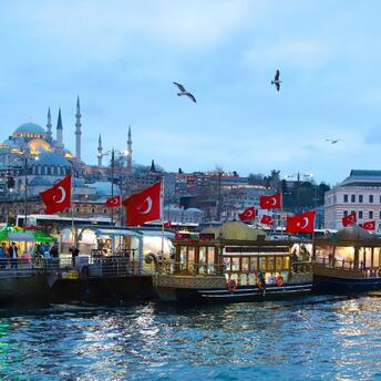 Traditional Turkish boats with flags docked at a busy waterfront in Istanbul