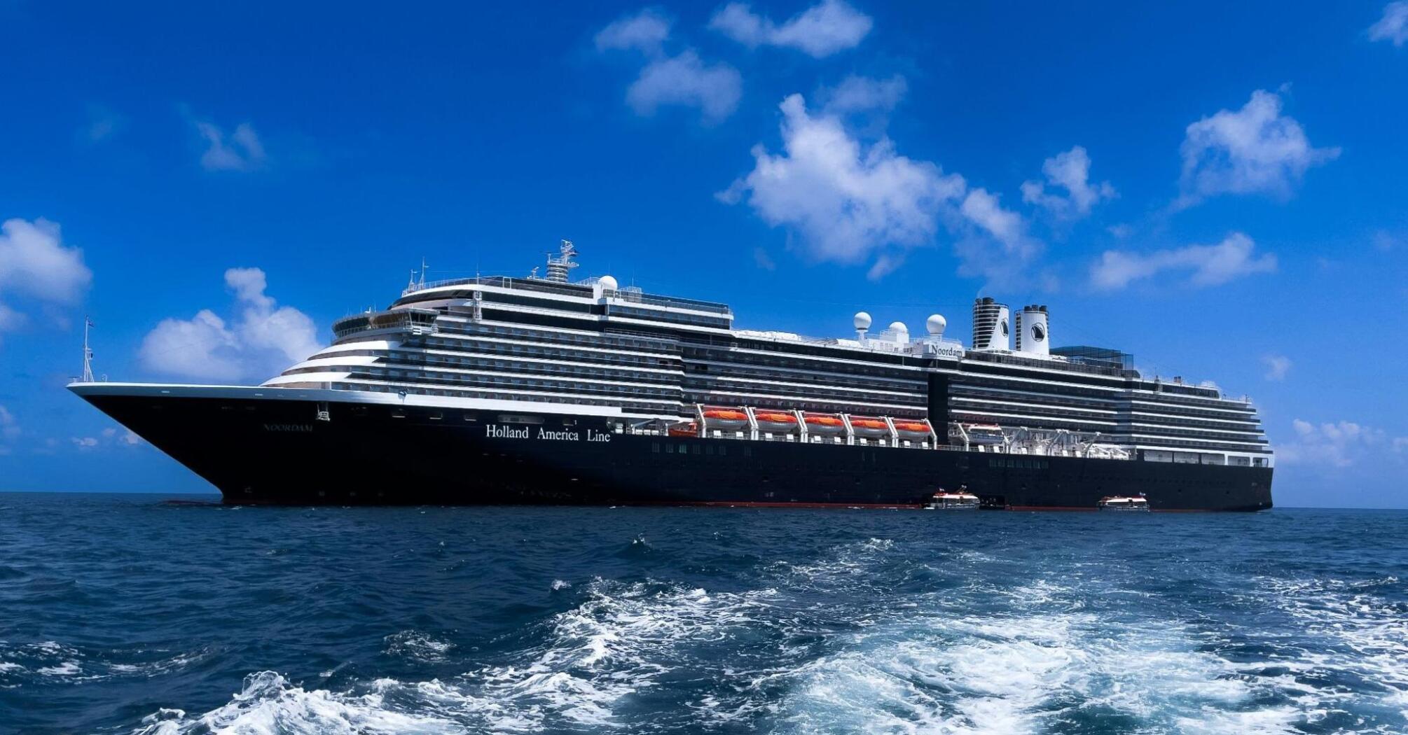 A Holland America Line cruise ship sailing on a clear blue sea under a bright sky