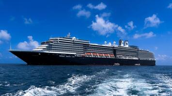 A Holland America Line cruise ship sailing on a clear blue sea under a bright sky