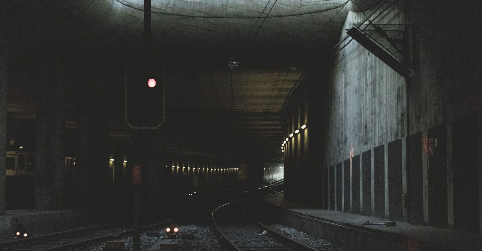 Interior of a dark railway tunnel with a red signal light